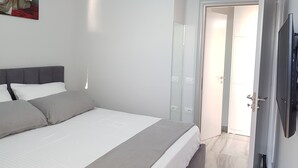 Une chambre moderne avec un grand lit, un téléviseur à écran plat et une porte donnant sur une autre pièce.
