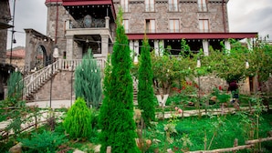 Un edificio de piedra con techo rojo, un balcón y una escalera que lleva a la entrada.