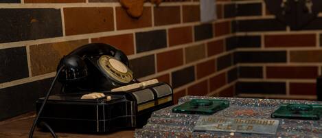 A vintage rotary dial telephone on a wooden table, a decorative key, and a nameplate with Cyrillic text.