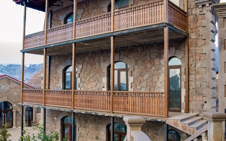 A multi-story building with a stone facade, balconies, and a curved staircase leading to the entrance.
