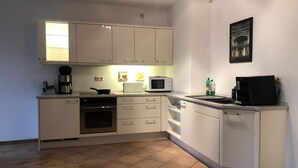 A compact kitchen with white cabinets, a microwave, a coffee maker, and a toaster. - Maison Euba am Zeisigwald (Euba)
