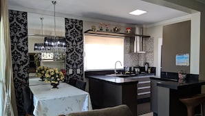 Une cuisine moderne dotée d’un îlot central, un coin repas avec une table et des chaises, et un espace de vie avec un canapé.