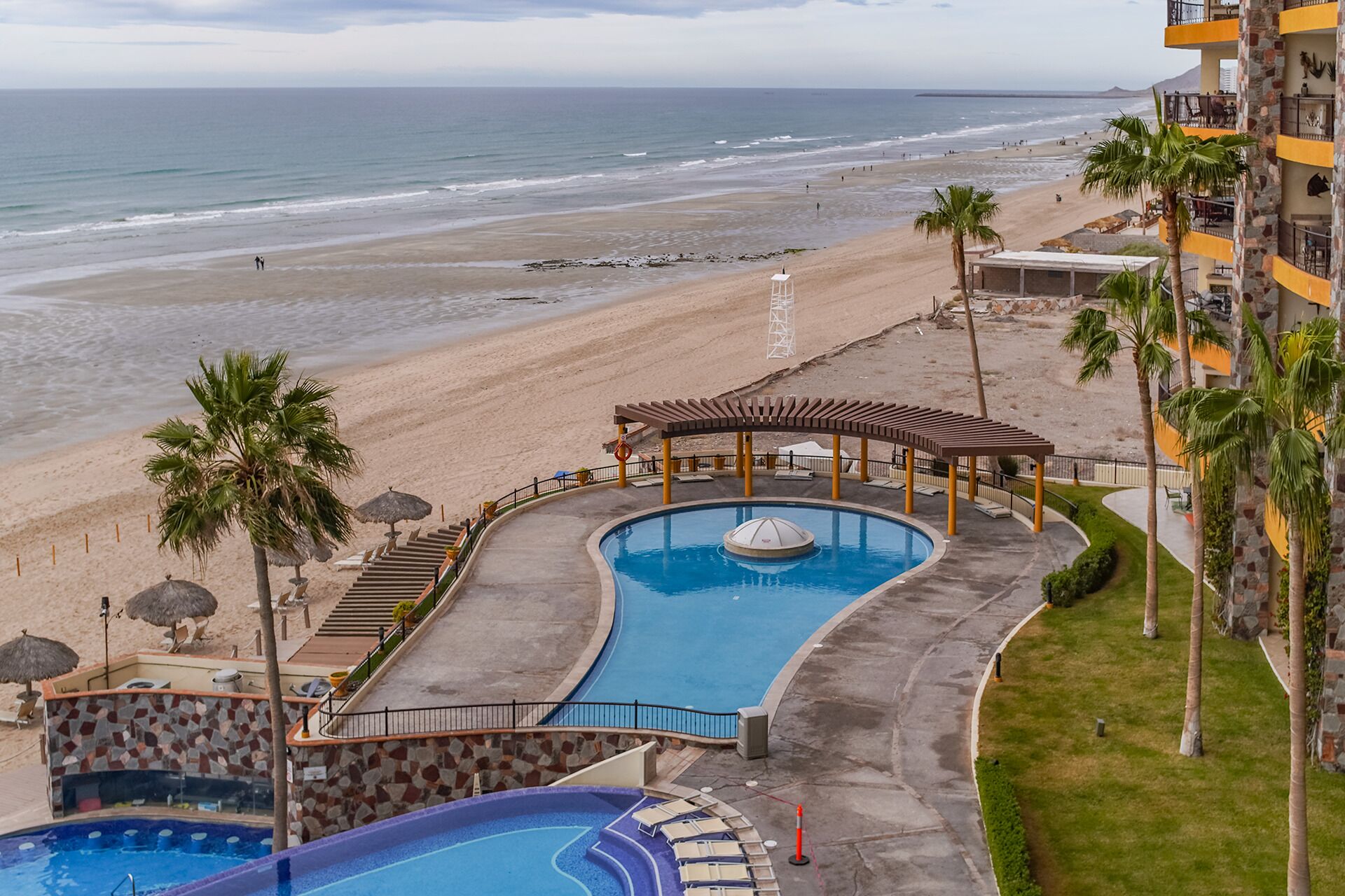 Un resort con piscina, acceso a la playa y vistas al océano.