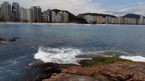 Un paysage urbain côtier avec de hauts immeubles, une plage et une côte rocheuse.