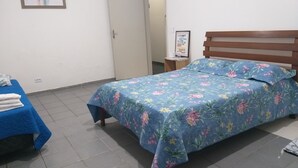 Une chambre à coucher avec un lit, une table de chevet, un tableau encadré au mur et une porte donnant sur une autre pièce.