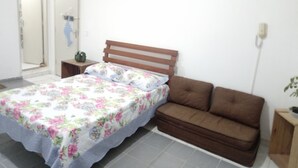 Une chambre à coucher avec un lit, un canapé marron, une table de chevet et un téléphone fixé au mur.