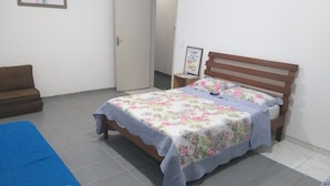 Une chambre à coucher avec un lit en bois, un tapis bleu, un canapé marron et une porte.