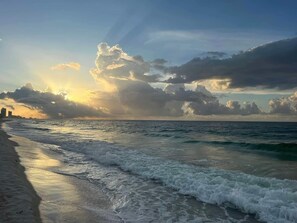 A beach with waves, a city skyline in the distance, and a cloudy sky. - Ride the TIDE Beachside! 2Bd, 1B, Free Parking! Steps 2 Sand! 200 5 Star Reviews (Gulf Shores)