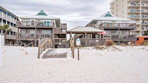 Een hotel aan het strand met meerdere balkons, een overdekte gang en een zandstrand.