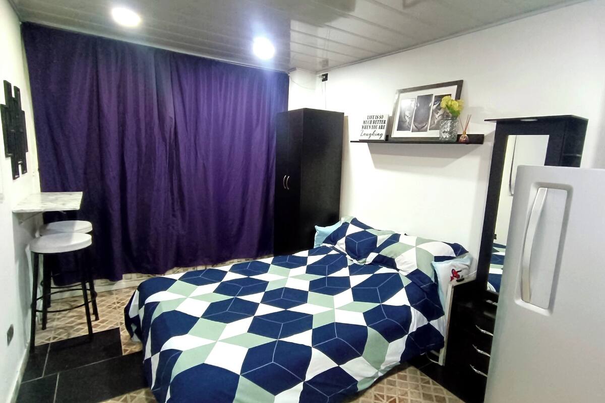 Ein kleiner, kompakter Raum mit Bett, Schreibtisch und Kleiderschrank.