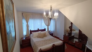 Quarto com cama, lustre, cômoda e espelho.