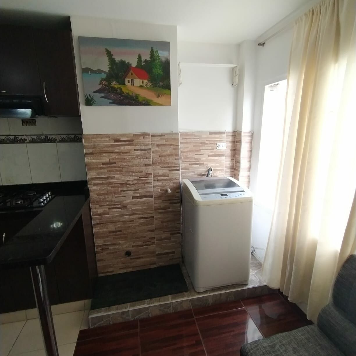 A compact kitchen with a built-in stove, a small sink, and a painting on the wall.