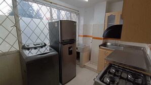 Uma cozinha compacta com fogão a gás, geladeira e pia.