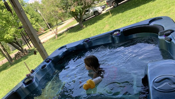 Un jacuzzi con una persona y un patito de juguete amarillo.