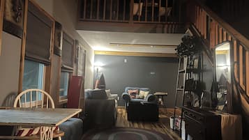 Una sala acogedora con una escalera, un comedor y una estantería.