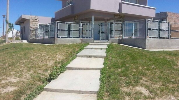 A modern two-story house with a flat roof and a large glass balcony. - Complejo Felesa Las Grutas (Las Grutas)