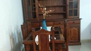 A dining area with a wooden table and chairs, a blue vase with flowers, and a wooden cabinet in the background. - Complejo Felesa Las Grutas (Las Grutas)