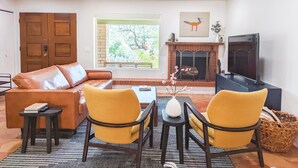 A living room with a sofa, two yellow chairs, a coffee table, a fireplace, and a TV.