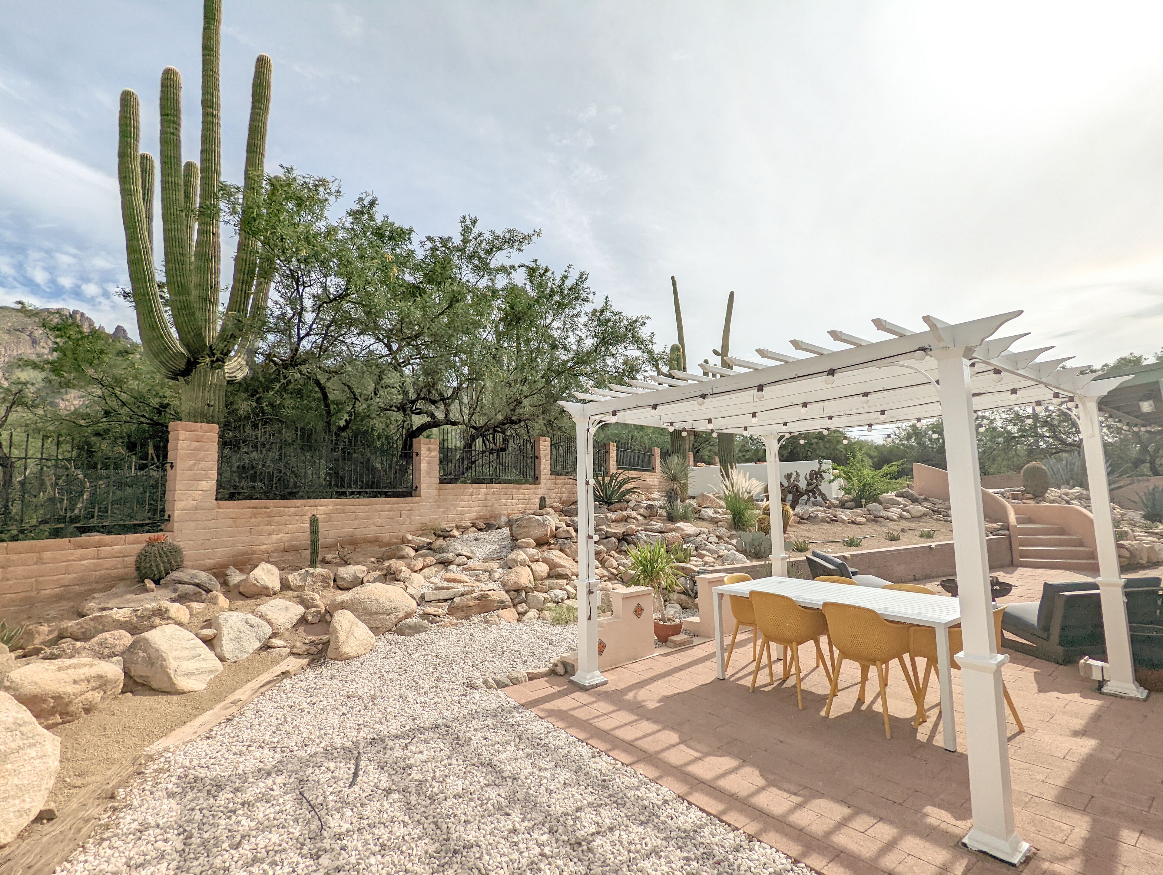 A patio area with a pergola, outdoor seating, and cacti.