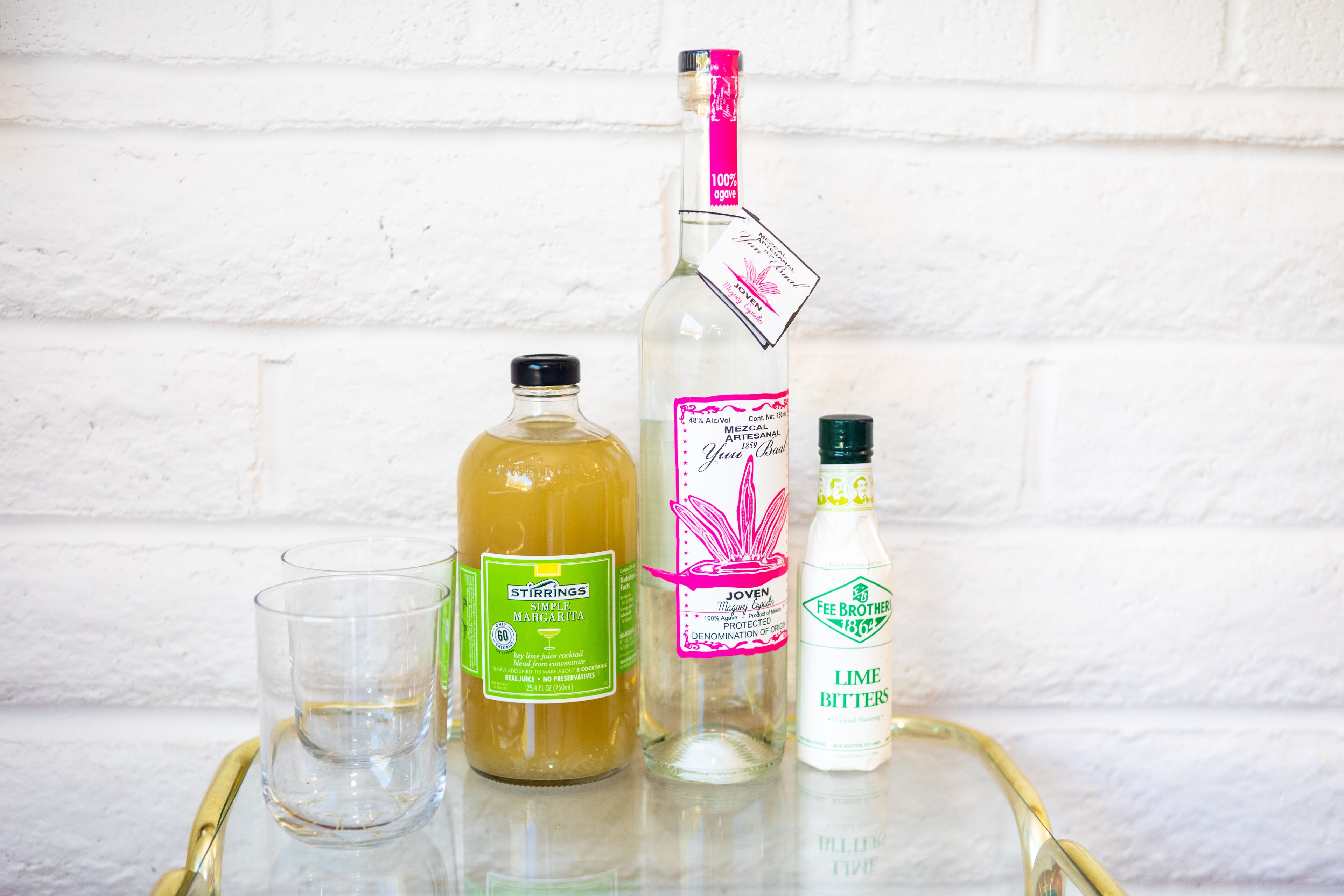 A glass tray with three bottles and a glass on it.
