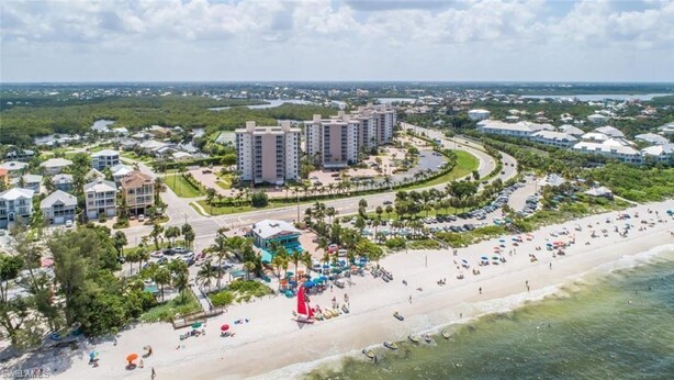 An aerial view of a coastal resort with multiple high-rise buildings, a sandy beach, and a marina. - Life's a beach and Tennis... (Bonita Springs)