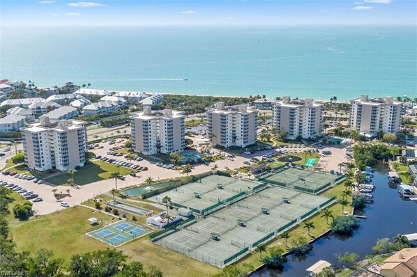 A coastal residential area with high-rise buildings, a parking lot, and a tennis court.