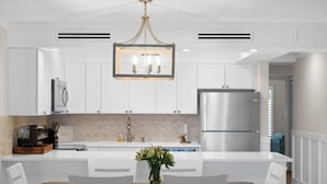Une cuisine moderne avec des meubles blancs, un îlot central et un lustre.