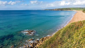 A coastal landscape with a sandy beach, clear blue sea, and rocky outcrops. - A beautiful, dog-friendly holiday home with magnificent views of two coastlines (Praa Sands)