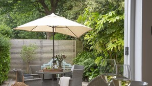 Un patio al aire libre con mobiliario de mimbre, una mesa y un paraguas grande.