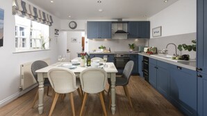 Una cocina moderna con armarios azules, una mesa de comedor con sillas y una ventana con cortinas.