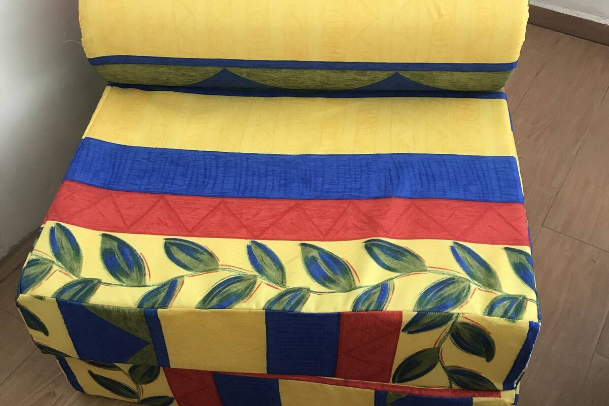 A colorful sofa with a geometric pattern in a room with wooden flooring.