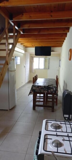A kitchen with a stove, a dining table with chairs, a refrigerator, and a staircase. - La casa de Titi (Querétaro)