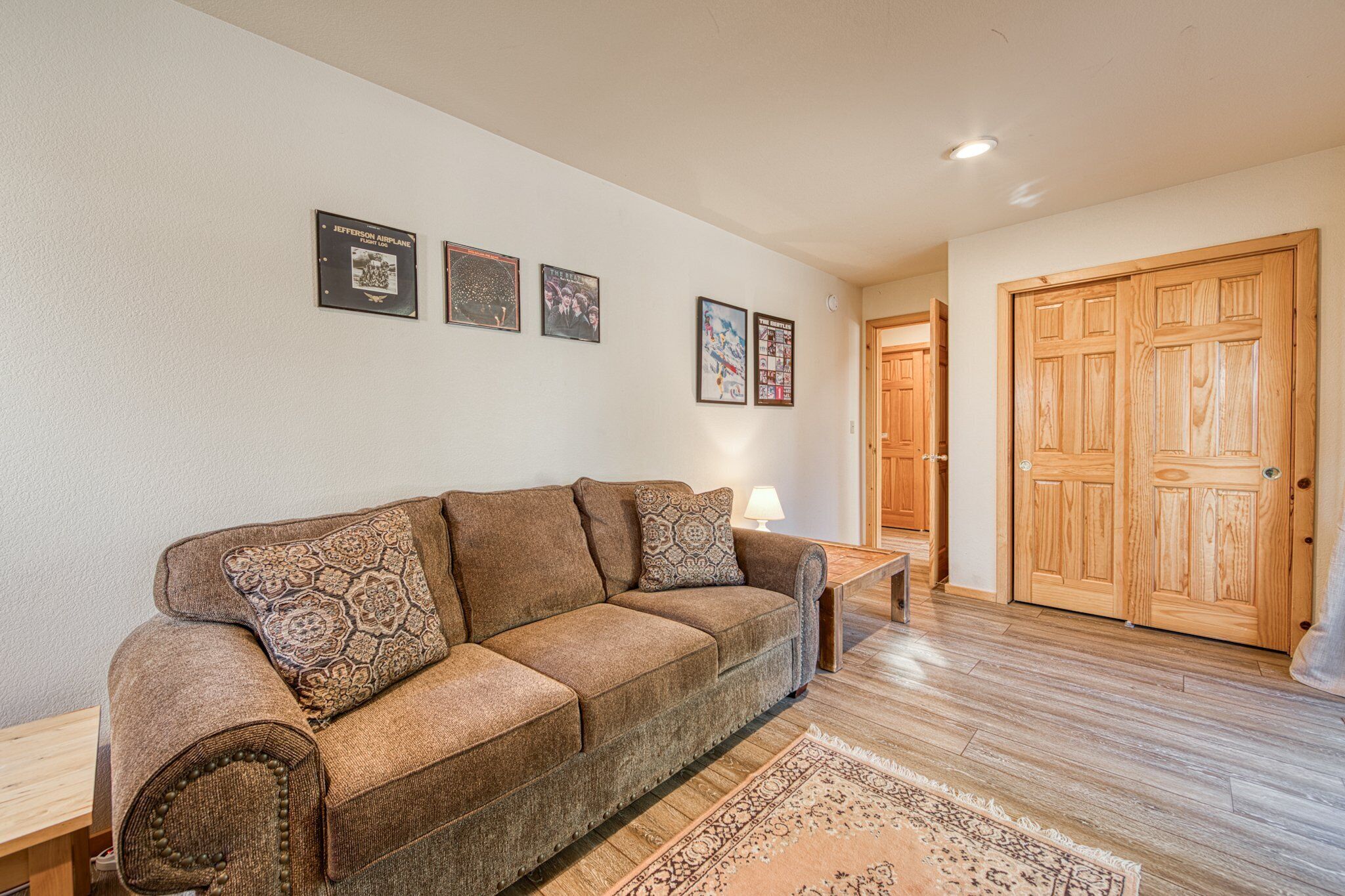 Un salon avec un canapé marron, un plancher en bois et une grande porte en bois.