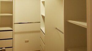 Un dressing avec de nombreuses étagères et tiroirs, un luminaire au plafond et un plancher en bois.