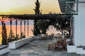 En terrasse med udendørs møbler, et pergola-tag og udsigt til vandet.