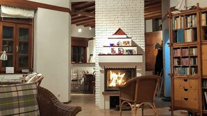 Ein gemütliches Wohnzimmer mit Kamin, Bücherregal und Essbereich mit Tisch für zwei Personen.
