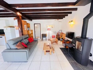 Ein Wohnzimmer mit Sofa, Couchtisch, Fernseher und Kaminofen.
