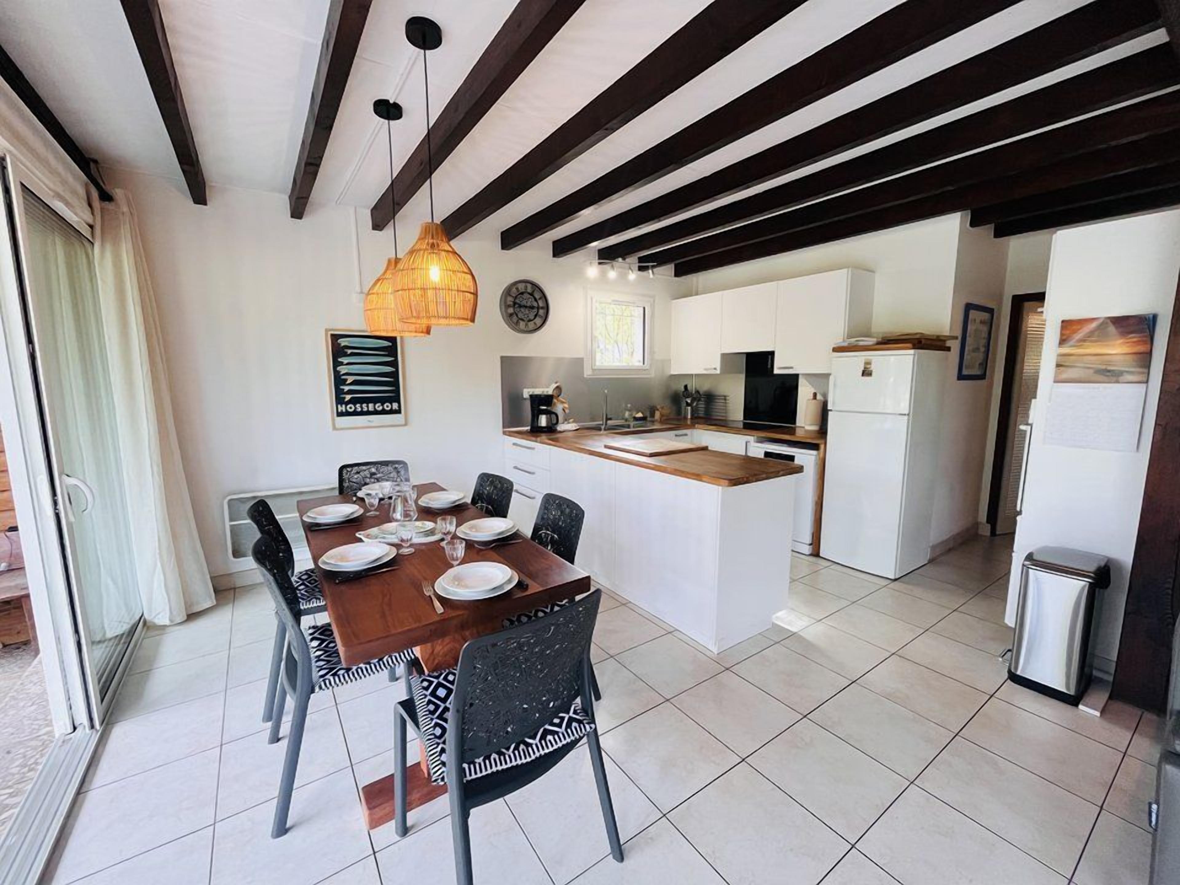 A modern kitchen with white cabinets, a wooden island, and a dining area with a table set for four.