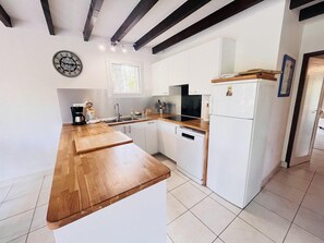 Eine Küche mit weißen Schränken, einer Holz Arbeitsplatte, einem Kühlschrank und einer Kaffeemaschine.