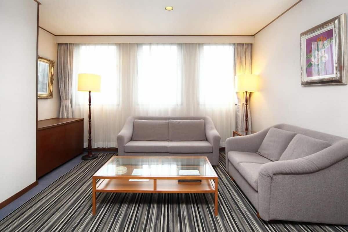 A hotel room with a sofa, a coffee table, a lamp, a picture frame, and a striped carpet.