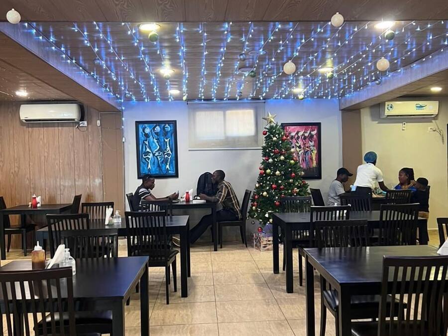 Un restaurante con paneles de madera, mesas, sillas y un árbol de Navidad decorado.