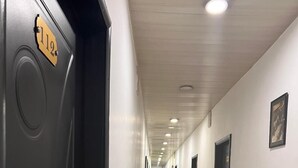 A long, narrow hallway with doors on both sides, numbered plaques, and recessed lighting. - Diana Hotel (Monrovia)