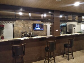 A bar area with a counter, stools, and a television screen. - Diana Hotel (Monrovia)