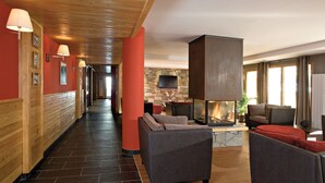 Una hall d'albergo con camino, divani e un lungo corridoio.