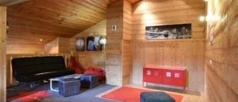 Interior acogedor de una cabaña de troncos con chimenea, zona de estar y un mueble de almacenamiento rojo.