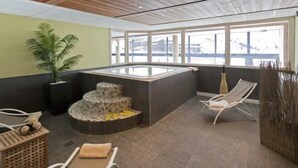 A spa area with a hot tub, seating, and a staircase leading to a higher level.
