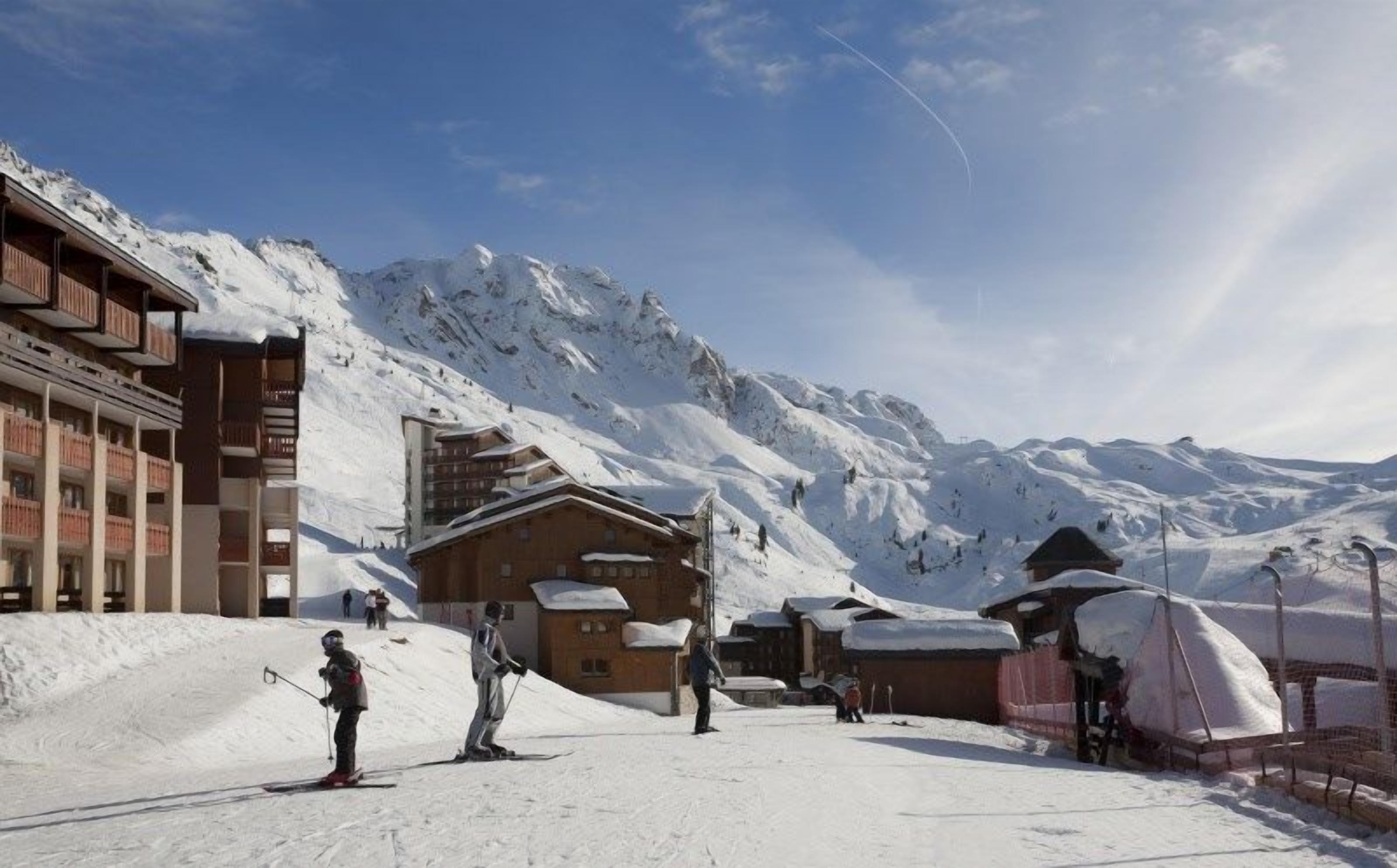 Una stazione sciistica con edifici in legno e montagne innevate sullo sfondo.