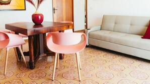 A dining area with a wooden table, pink chairs, and a vase with dried plants. - Apartment Pinta by Interhome (Marina di Caronia)
