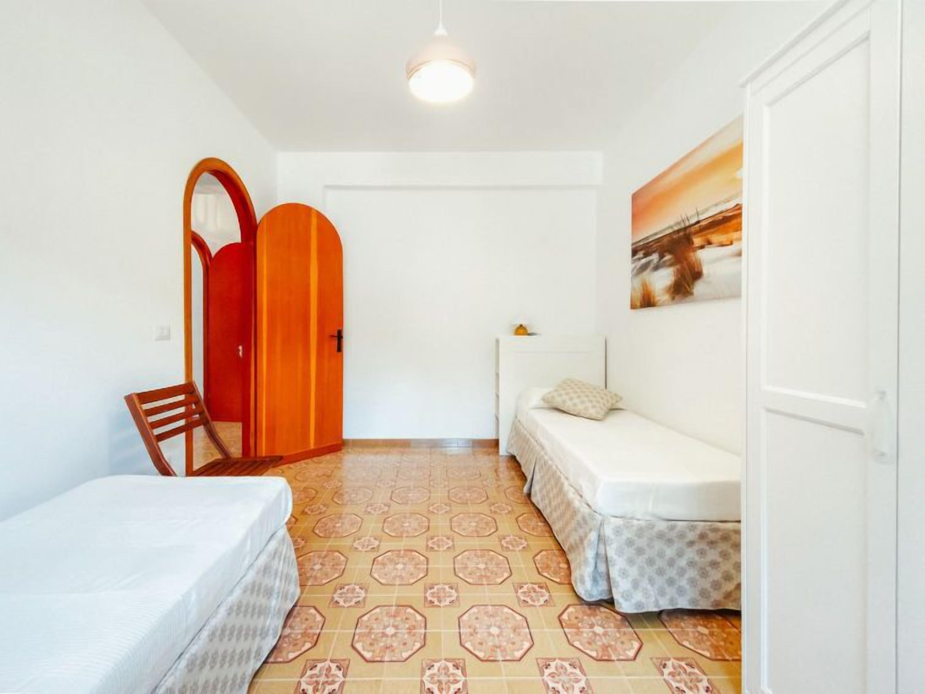 A small, clean room with a bed, a chair, and a door.
