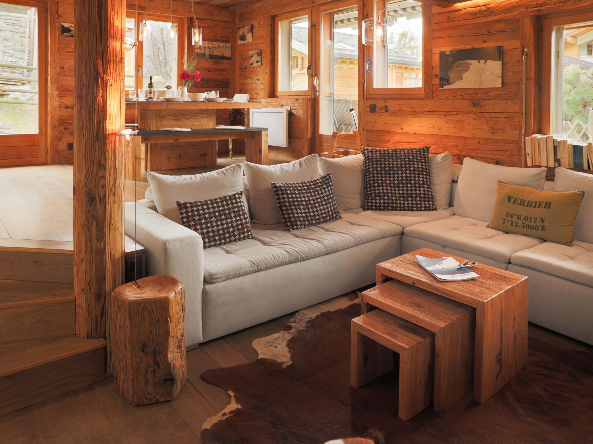 L’intérieur chaleureux d’un chalet en rondins, avec un ensemble de canapés, une table basse en bois et un tapis en peau de vache.